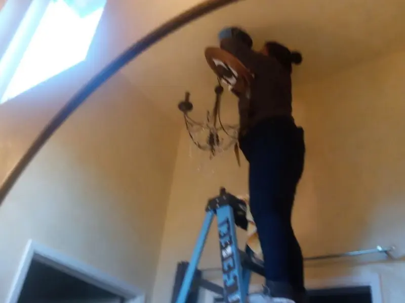 Electrician installing a chandelier in a Tecumseh residence